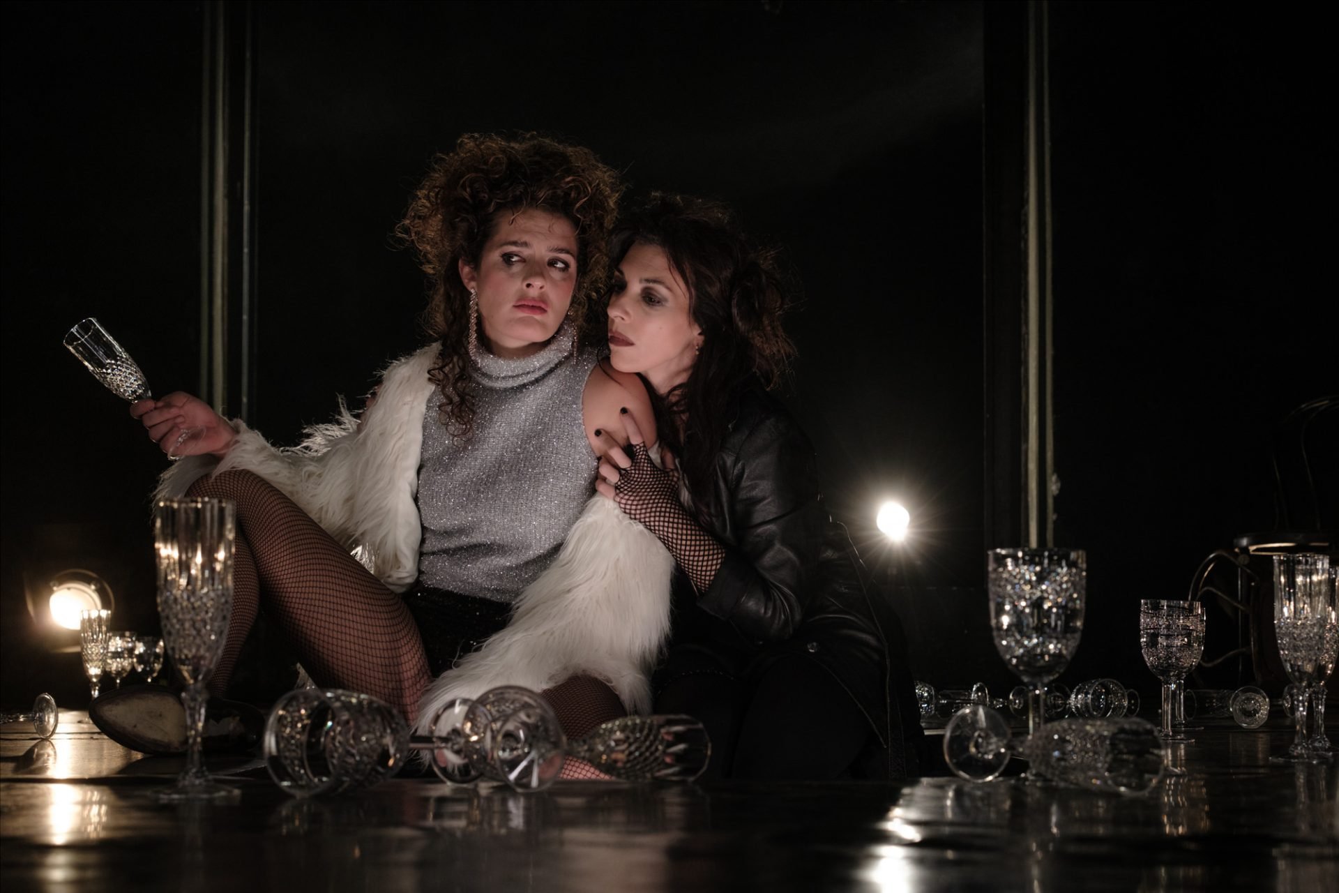 Two performers in Poreia Theatre’s Electra amid overturned crystal glassware